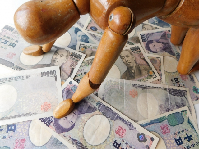 お金の上でうなだれる。御殿場市で借金返済の相談は無料でできます